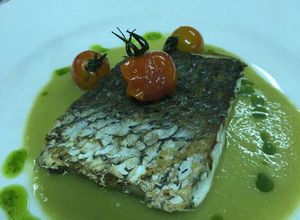 Una foto de Corvina negra con crema de espárragos y cherris salteados