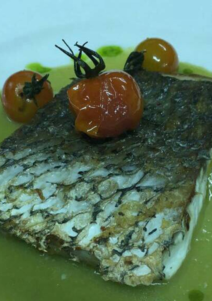 Una foto de Corvina negra con crema de espárragos y cherris salteados