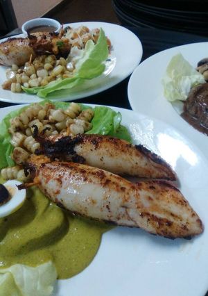Una foto de Calamar relleno de mariscos con guarnición de choclo al comino