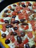 Pizza con tomates frescos, olivas negras y ajo picado