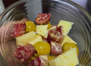 Una foto de Aperitivo de fuet, queso y olivas bañados en vermut y AOVE