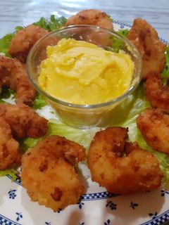Una foto de Camarones empanizados acompañados de una salsa holandesa