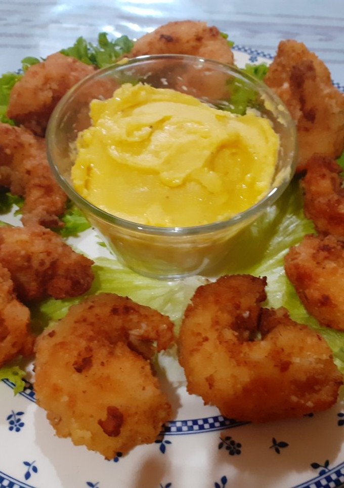 Una foto de Camarones empanizados acompañados de una salsa holandesa