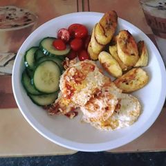 A picture of Fried plantain with fried egg served with cucumber and fresh tomatoes.