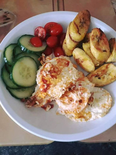 A picture of Fried plantain with fried egg served with cucumber and fresh tomatoes.