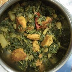A picture of Spinach curry with pakoda.