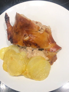 Una foto de Cochinillo asado al horno con piel crujiente y patatas panaderas