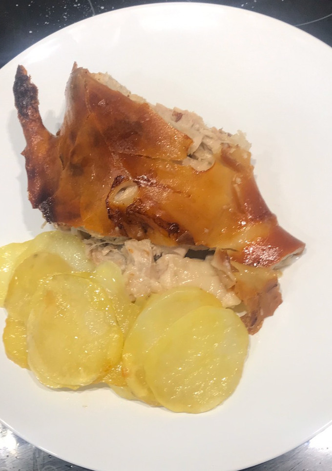 Una foto de Cochinillo asado al horno con piel crujiente y patatas panaderas
