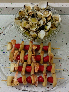 Una foto de Brochetas de chocos y langostinos con almejas al ajillo