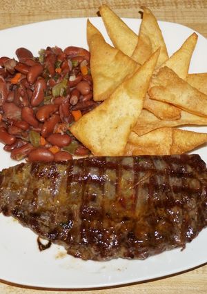 A picture of Grilled Flank Steak with Stewed Kidney Beans and Homemade Tortilla Chips.