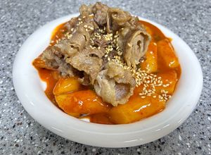 Hình của món Bánh gạo cay ăn kèm ba chỉ bò áp chảo.