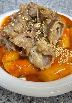 Hình của món Bánh gạo cay ăn kèm ba chỉ bò áp chảo.