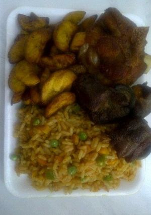 A picture of Jolly rice with fried goat meat and plantain.