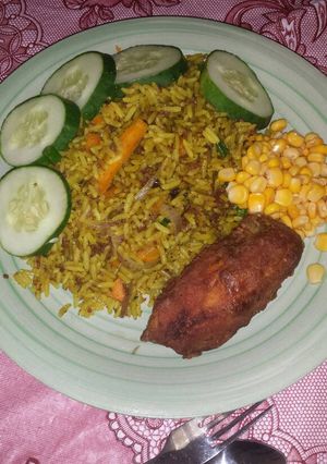 A picture of Fried rice garnished with sweet corn, cucumber and fried chicken.