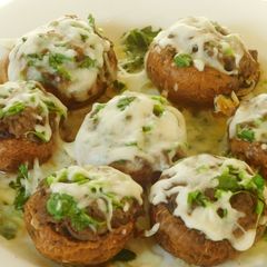 A picture of Hummus stuffed chessey mushrooms.
