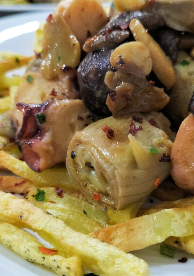Una foto de Wok de alcachofas, setas y pulpo, con patatas paja