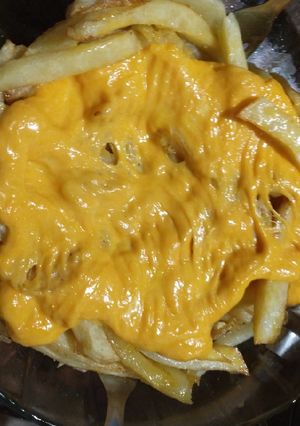 Una foto de Papas fritas con queso cheddar
