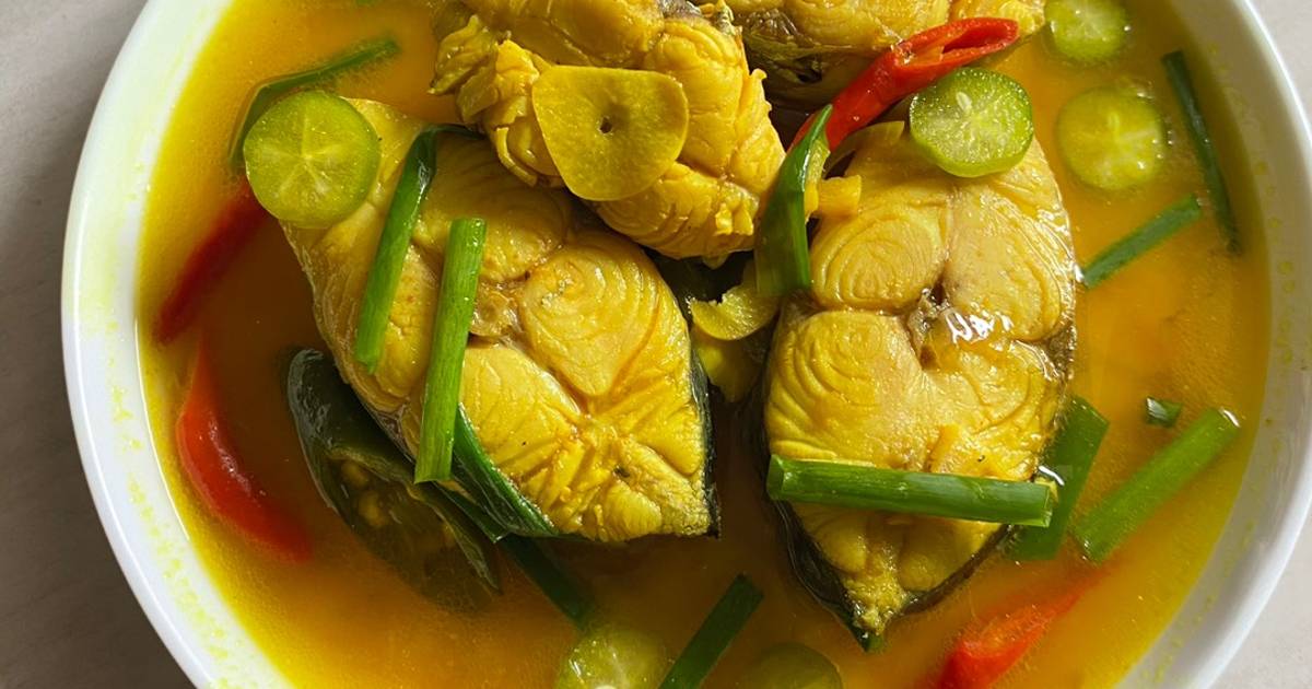 Semangkuk ikan kuah kuning dengan warna cerah dari kunyit, disajikan hangat dengan rempah segar