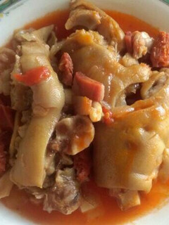 Una foto de Manitas de cerdo con tomate y un toquecito de picante