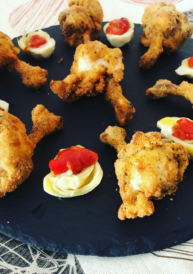 Una foto de Jamoncitos de alas de pollo al limón con corazones rotos de alcachofa y pimiento asado