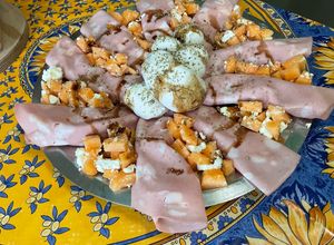Une photo de Salade composée de melon à la mortadelle, feta, mozzarella tressée, origan et crème de balsamique
