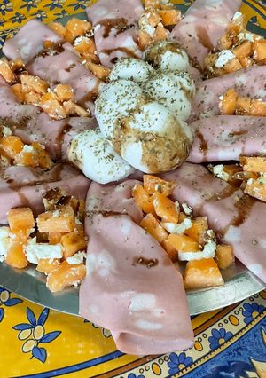 Une photo de Salade composée de melon à la mortadelle, feta, mozzarella tressée, origan et crème de balsamique
