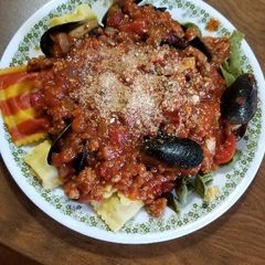 A picture of Spinach Fettuccine with Lobster Ravioli, Mussels, & Meat Sauce.
