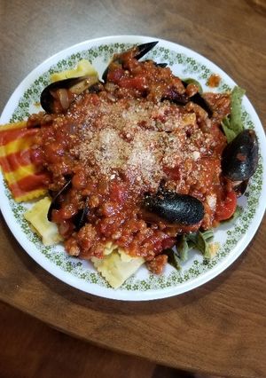 A picture of Spinach Fettuccine with Lobster Ravioli, Mussels, & Meat Sauce.