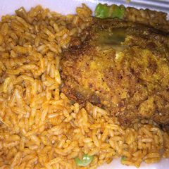 A picture of Jollof rice with chicken breast.