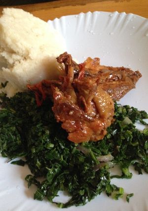 A picture of Deep fried chicken served with kale and ugali.