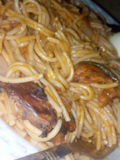 A picture of Spaghetti jollof with dried fish and boiled eggs.