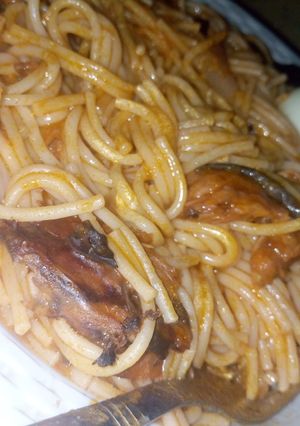 A picture of Spaghetti jollof with dried fish and boiled eggs.