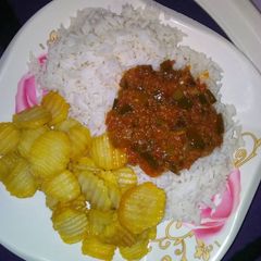 A picture of Rice and stew with chips.