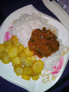 A picture of Rice and stew with chips.