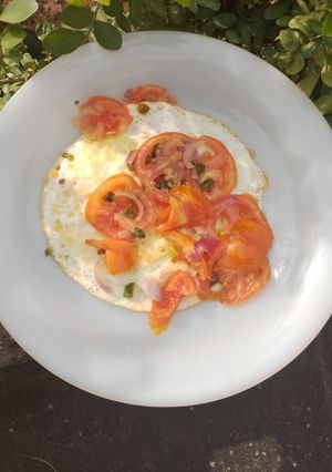 A picture of Fried Egg Garnished with Fresh Vegetables.