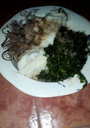 A picture of Ugali served with sukuma and beef.