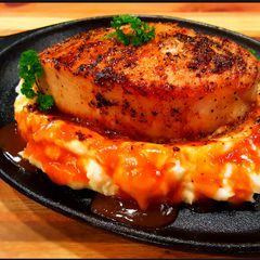 A picture of Mike's Thick Cut Top Loin Pork Chops Over Mashed Potatoes.
