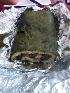 Una foto de Tamal enrollado de frijol negro, masa y hoja santa