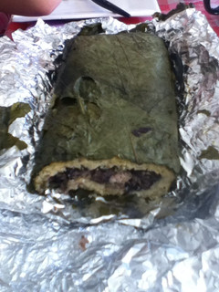 Una foto de Tamal enrollado de frijol negro, masa y hoja santa