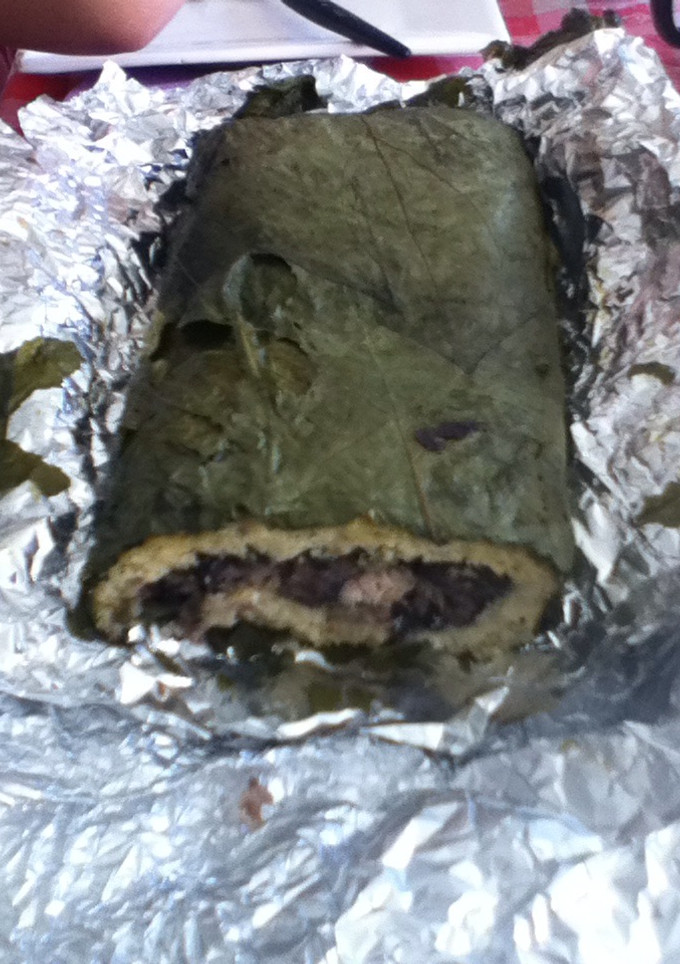 Una foto de Tamal enrollado de frijol negro, masa y hoja santa