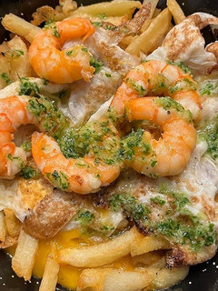 Una foto de Patatas fritas con huevos rotos y langostinos al ajillo