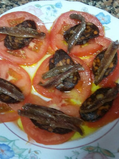 Una foto de Tomates en rodajas con anchoas y morcilla