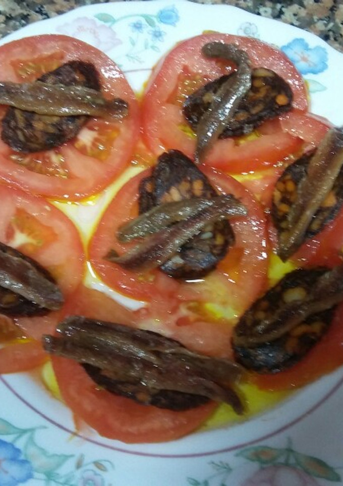 Una foto de Tomates en rodajas con anchoas y morcilla