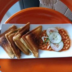 A picture of Toast garnished with Baked beans and Cucumber.