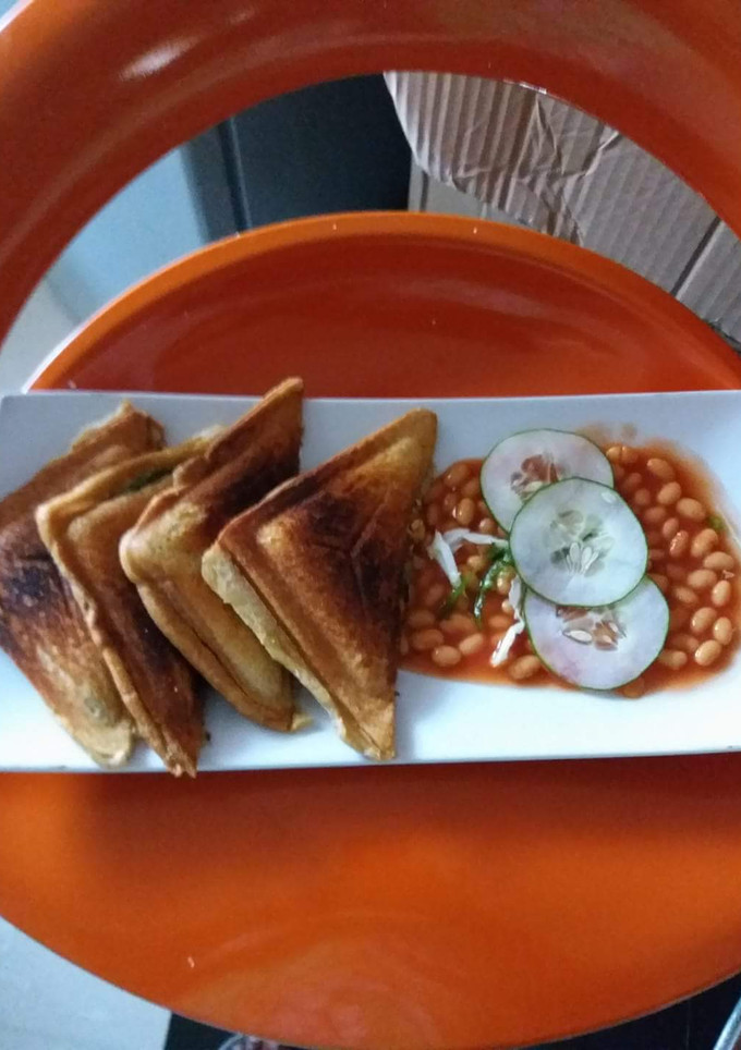 A picture of Toast garnished with Baked beans and Cucumber.