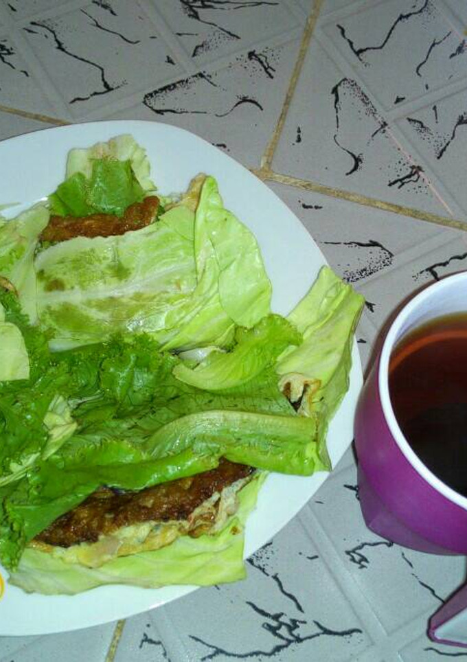 A picture of Fried Eggs wrapped in cabbage and lettuce with Tea.
