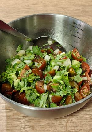 Una foto de Ensalada del día, con rúcula, tomate y pepinillos frescos