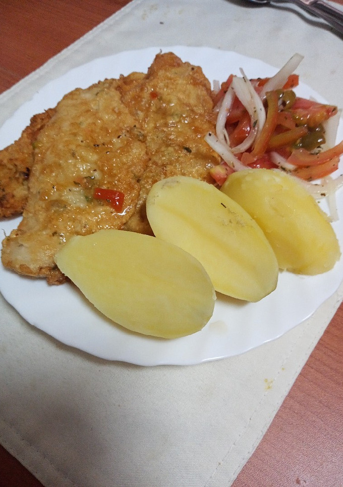 Una foto de Merluza adobada, rebozada y frita con papas cocidas y ensalada