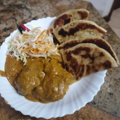 A picture of Butter chicken served with buttered Naan bread.