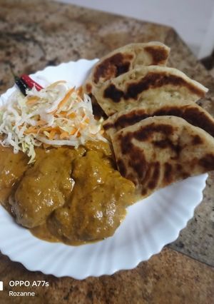 A picture of Butter chicken served with buttered Naan bread.